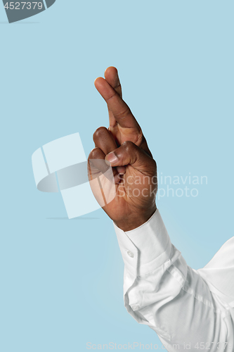 Image of Male hand demonstrating a gesture of luck isolated on blue background