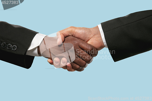 Image of Two male hands shaking isolated on blue studio background