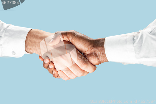 Image of Two male hands shaking isolated on blue studio background