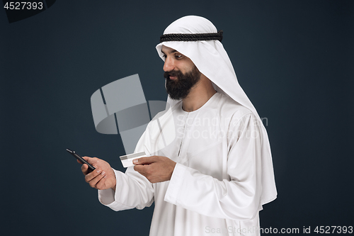 Image of Arabian saudi man on dark blue studio background