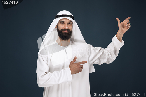 Image of Arabian saudi man on dark blue studio background