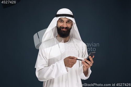 Image of Arabian saudi man on dark blue studio background