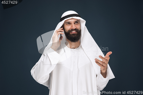 Image of Arabian saudi man on dark blue studio background