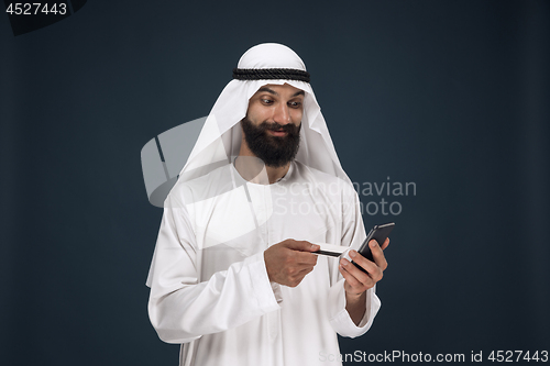 Image of Arabian saudi man on dark blue studio background