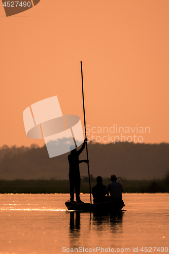 Image of Men in a boat on a river silhouette