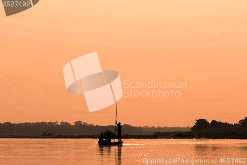 Image of Men in a boat on a river silhouette