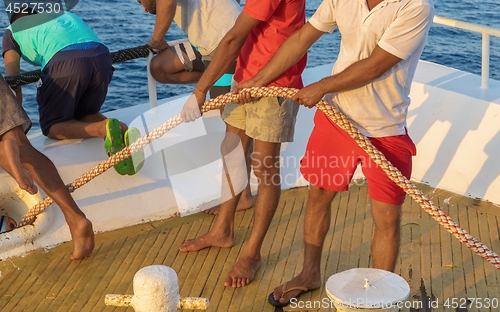 Image of Man pulling rope on boat