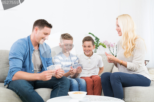 Image of Happy young family playing card game at home.