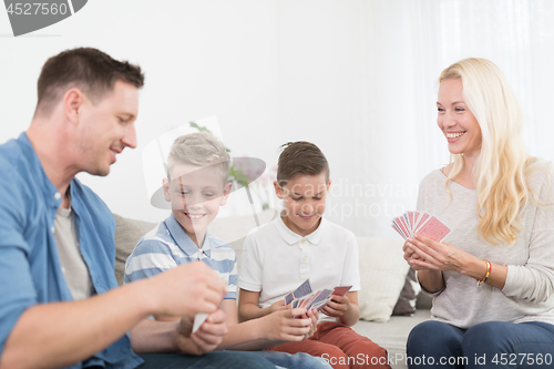 Image of Happy young family playing card game at home.