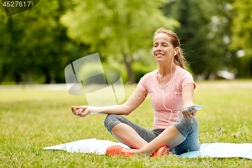 Image of woman with smartphone and hones meditating at park