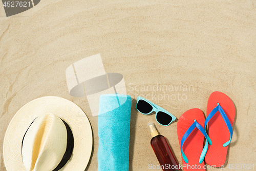 Image of straw hat, flip flops and sunglasses on beach sand