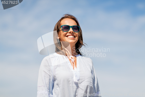 Image of happy smiling woman in sunglasses over sky