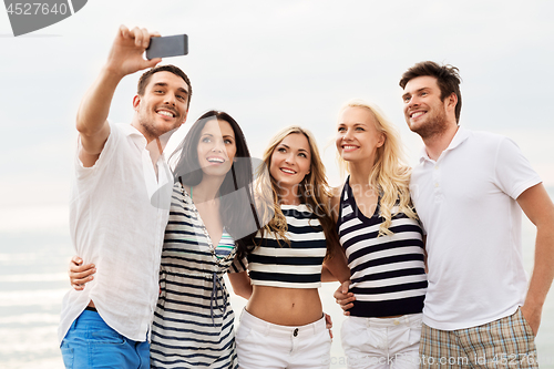 Image of happy friends taking selfie on summer beach