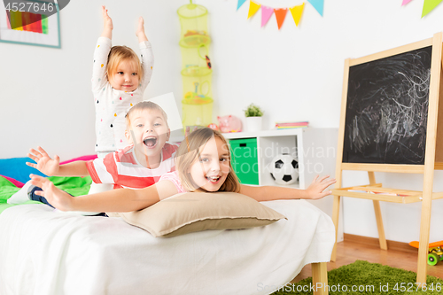 Image of happy little kids having fun in bed at home