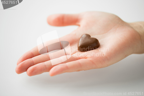 Image of close up of hand with heart shaped chocolate candy