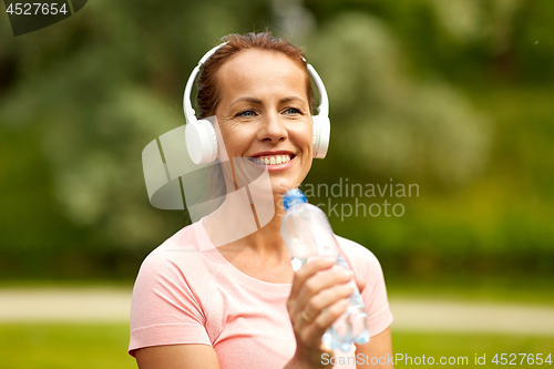 Image of woman in headphones with bottle of water at park