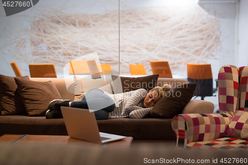 Image of woman sleeping on a sofa  in a creative office