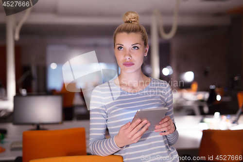 Image of woman working on digital tablet in night office