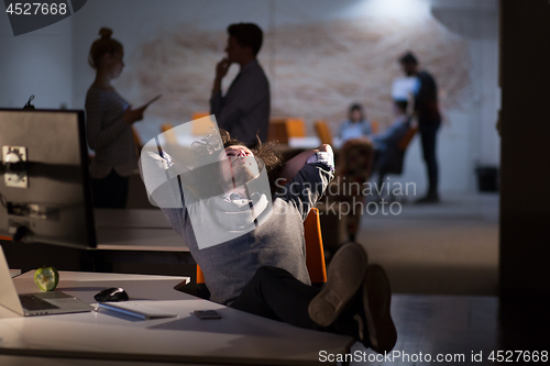 Image of businessman sitting with legs on desk at office
