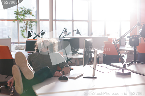 Image of businessman sitting with legs on desk