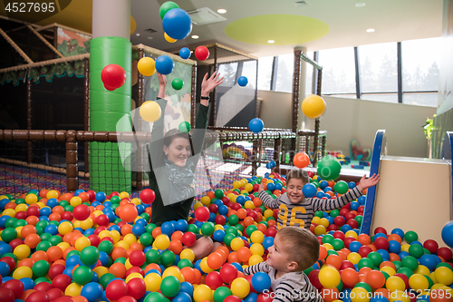 Image of Young mom with her kids in a children\'s playroom