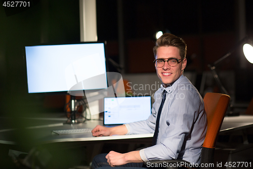 Image of man working on computer in dark office