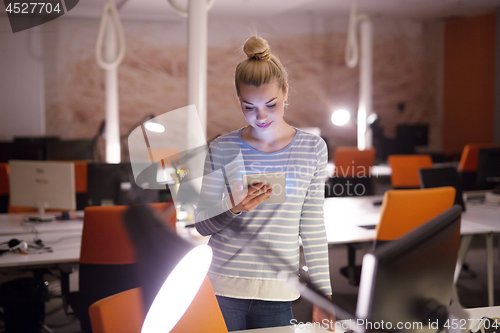 Image of woman working on digital tablet in night office