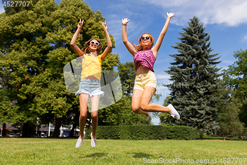 Image of happy teenage girls jumping at summer park