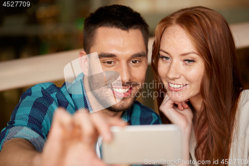 Image of couple taking selfie by smartphone at restaurant