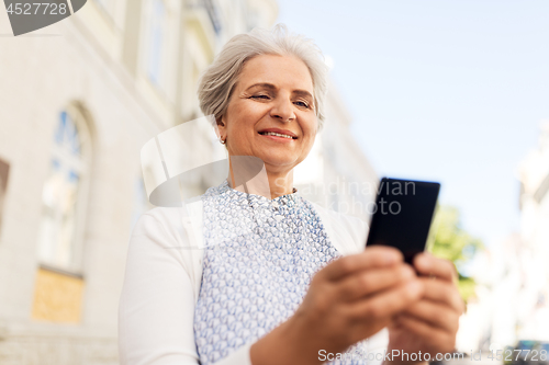Image of happy senior woman with smartphone in summer