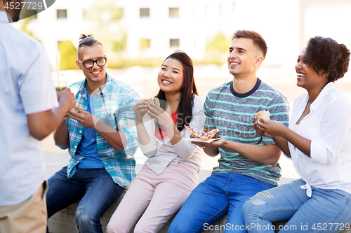 Image of friends eating pizza and sandwiches in park