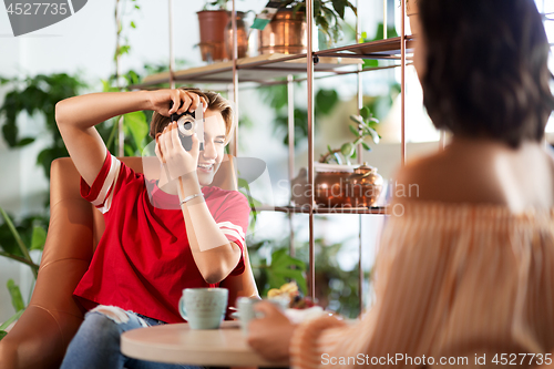 Image of women drinking coffee and photographing at cafe