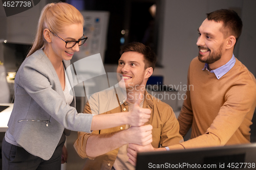 Image of business team making thumbs up gesture at office