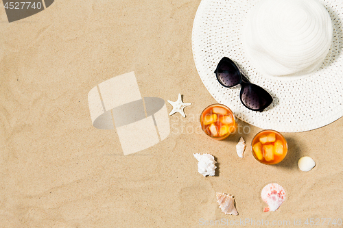 Image of cocktails, sun hat and sunglasses on beach sand