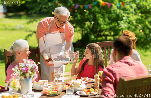 Image of family having dinner or barbecue at summer garden