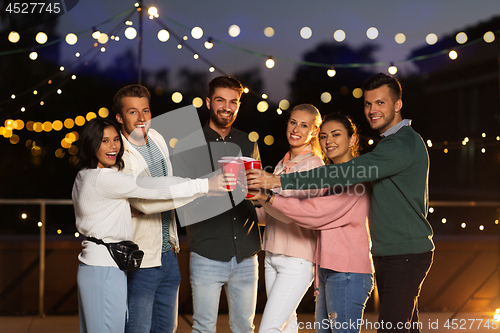 Image of friends clinking party cups on rooftop at night