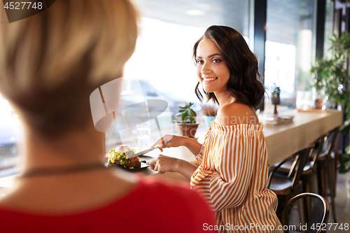 Image of female friends eating at restaurant