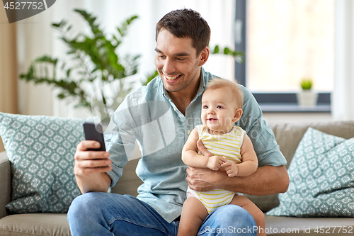 Image of father with baby daughter using smartphone at home