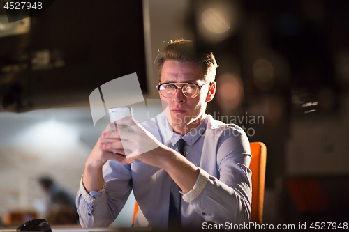 Image of man using mobile phone in dark office