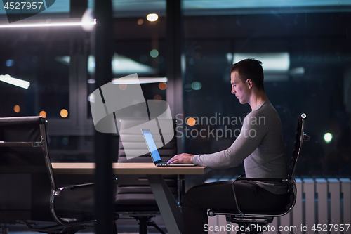 Image of man working on laptop in dark office