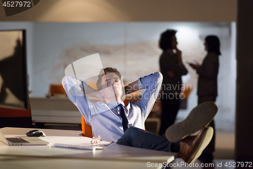 Image of businessman sitting with legs on desk at office