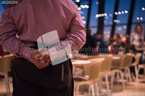 Image of waiter standing with hands behind his back
