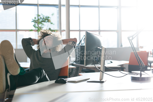 Image of businessman sitting with legs on desk