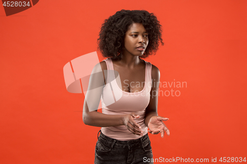 Image of Beautiful female half-length portrait isolated on red studio backgroud. The young emotional surprised woman