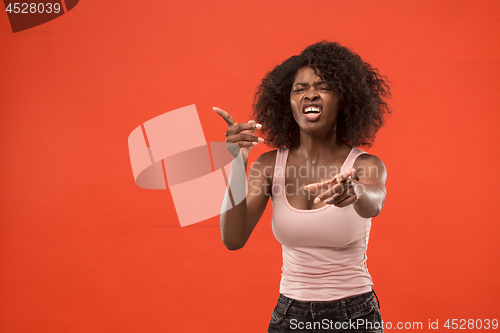 Image of Beautiful female half-length portrait isolated on red studio backgroud. The young emotional surprised woman