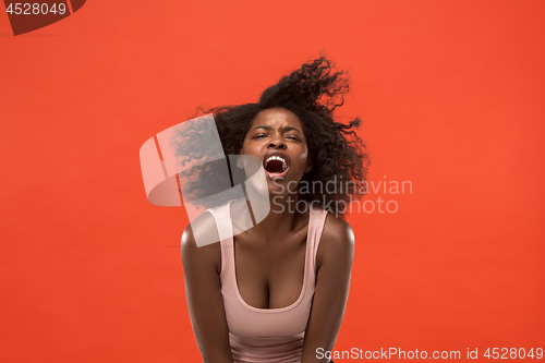 Image of The young emotional angry woman screaming on red studio background