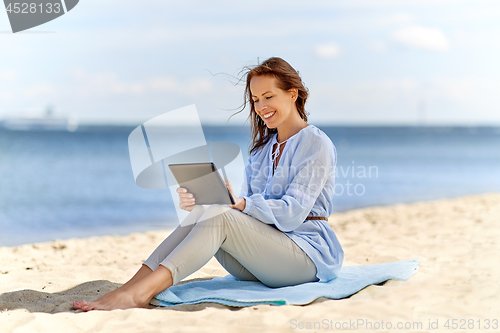 Image of happy smiling woman with tablet pc on summer beach