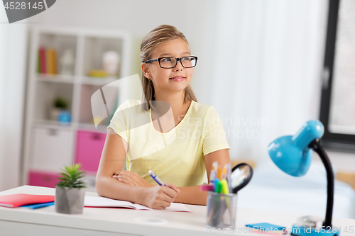 Image of happy student girl doing homework at home