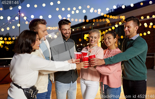 Image of friends clinking party cups on rooftop at night