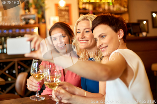 Image of women taking selfie by smartphone at wine bar